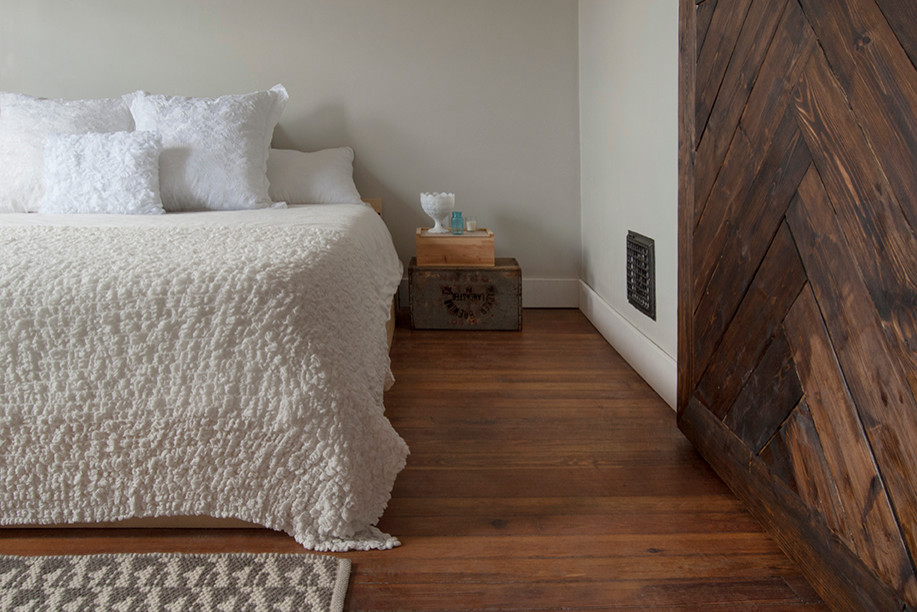 Photo of a mid-sized eclectic master bedroom in Columbus with beige walls and medium hardwood floors.