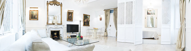 Exemple d'un grand salon chic fermé avec un mur blanc, un sol en carrelage de porcelaine, une cheminée standard, un manteau de cheminée en pierre et un sol beige.