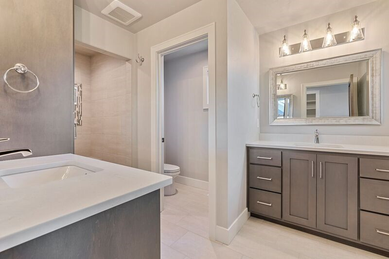 Example of a transitional master ceramic tile alcove shower design with shaker cabinets, gray cabinets, an undermount sink, quartz countertops, a hinged shower door and white countertops
