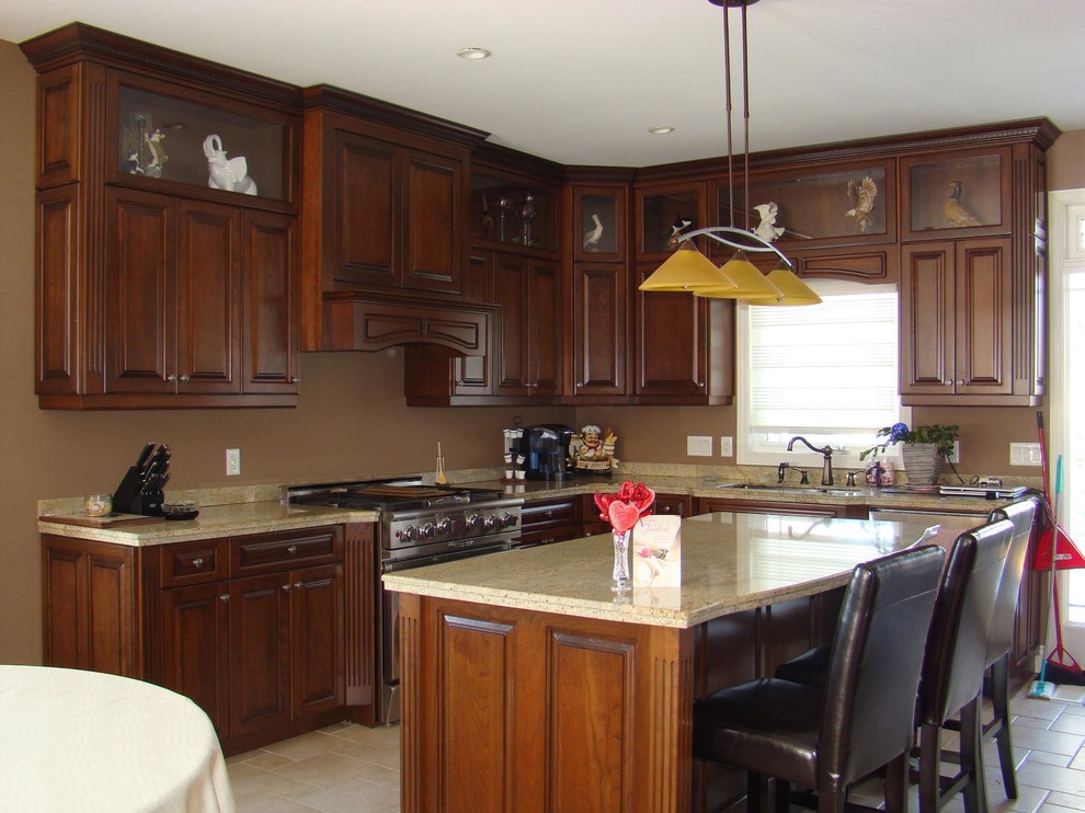 Mid-sized traditional l-shaped separate kitchen in Toronto with an undermount sink, raised-panel cabinets, dark wood cabinets, limestone benchtops, stainless steel appliances, travertine floors, with island and beige floor.