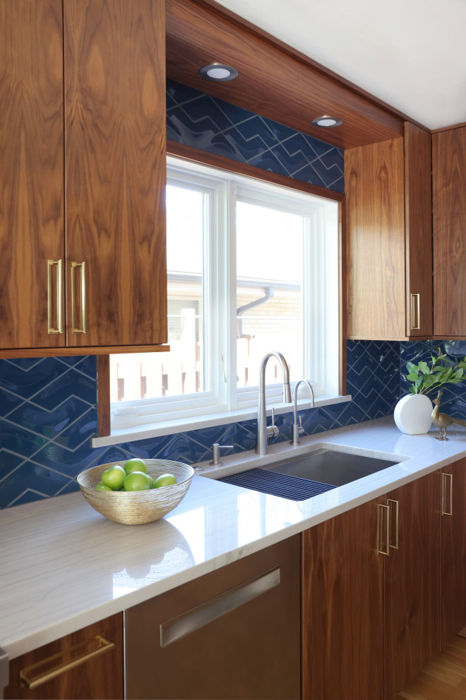 Photo of a mid-sized midcentury eat-in kitchen in Chicago with a single-bowl sink, flat-panel cabinets, medium wood cabinets, quartzite benchtops, blue splashback, ceramic splashback, stainless steel appliances, light hardwood floors, with island and white benchtop.