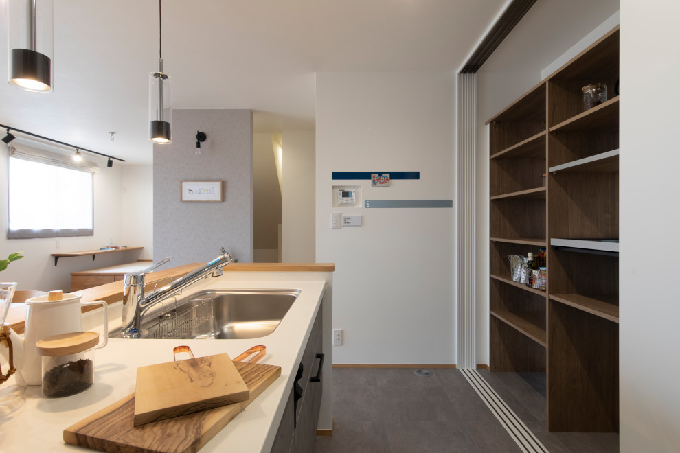 Imagen de cocina escandinava abierta con puertas de armario blancas, salpicadero marrón, suelo vinílico, suelo gris, encimeras marrones y papel pintado