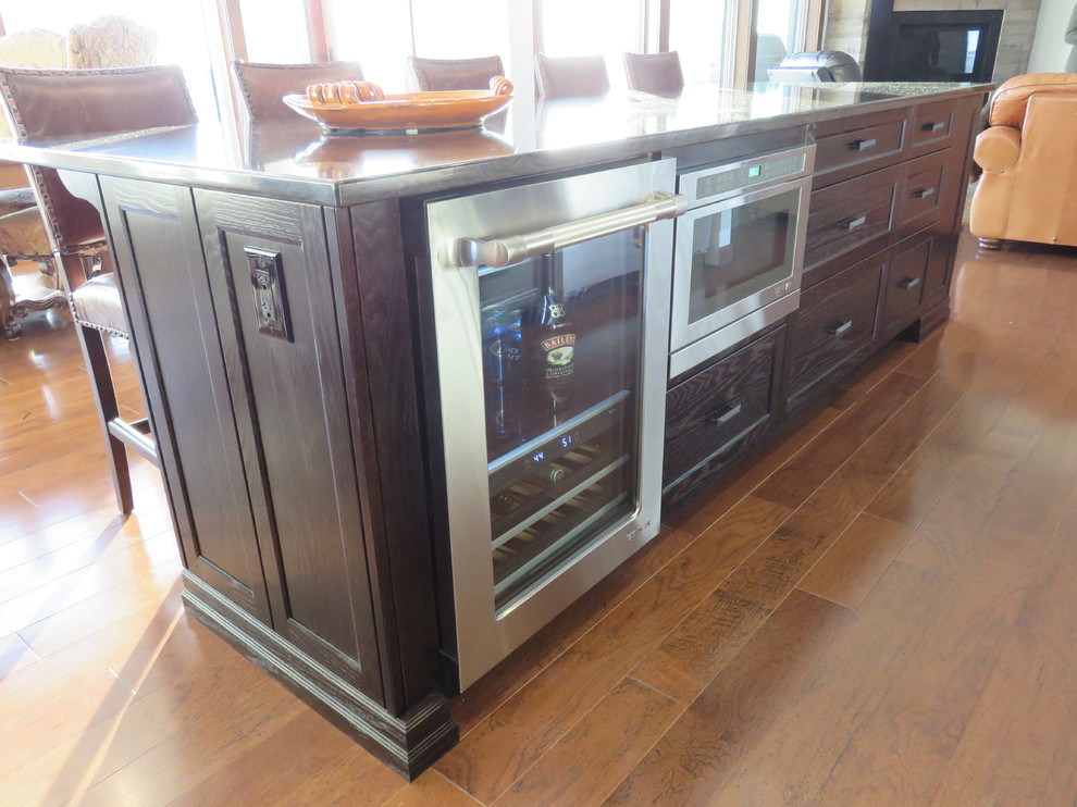 Example of a large transitional l-shaped dark wood floor open concept kitchen design with recessed-panel cabinets, dark wood cabinets, quartz countertops, stainless steel appliances, an island and an undermount sink
