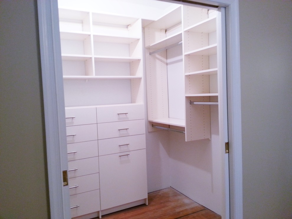 Design ideas for a modern gender-neutral walk-in wardrobe in New York with flat-panel cabinets, white cabinets and medium hardwood floors.