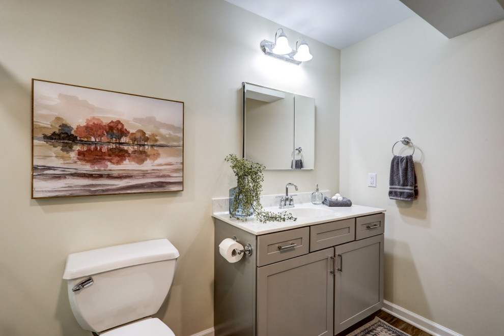 Klassisk inredning av ett mellanstort vit vitt en-suite badrum, med luckor med infälld panel, grå skåp, en dusch/badkar-kombination, en toalettstol med separat cisternkåpa, beige väggar, vinylgolv, ett integrerad handfat, marmorbänkskiva, brunt golv och dusch med skjutdörr