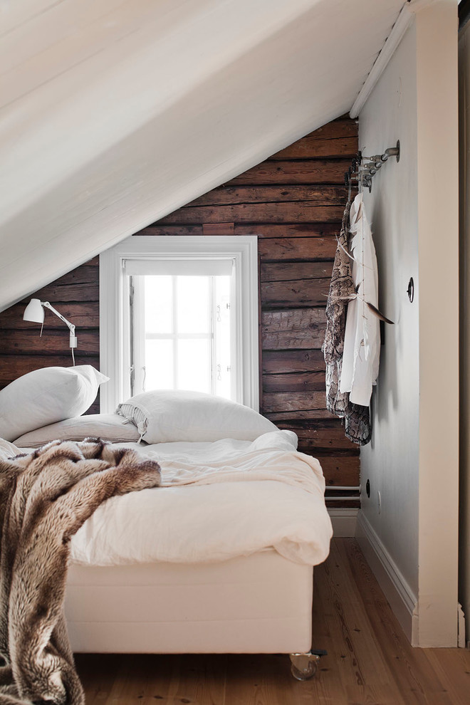 This is an example of a small scandinavian guest bedroom in Stockholm with light hardwood floors and white walls.