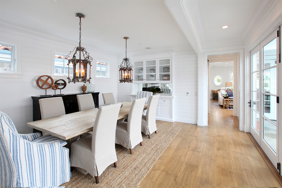 Country dining room in Orange County with white walls, medium hardwood floors and beige floor.