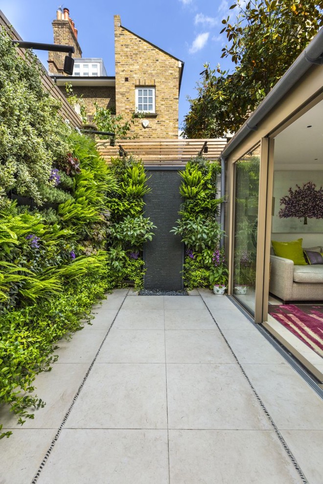 Photo of a contemporary patio in London with a vertical garden, concrete pavers and no cover.