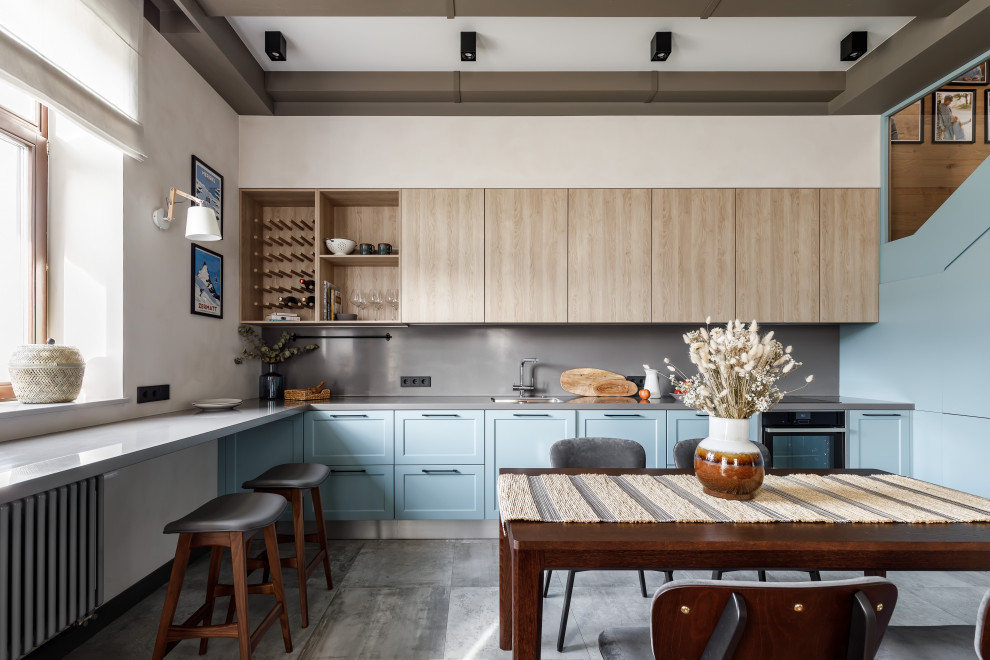 Design ideas for a large scandinavian l-shaped eat-in kitchen in Saint Petersburg with an undermount sink, shaker cabinets, blue cabinets, grey splashback, panelled appliances, porcelain floors, no island, grey floor, grey benchtop and exposed beam.