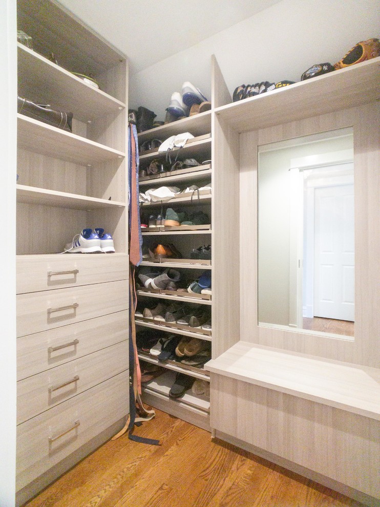 This is an example of a large transitional gender-neutral walk-in wardrobe in Chicago with flat-panel cabinets, light wood cabinets, medium hardwood floors and brown floor.