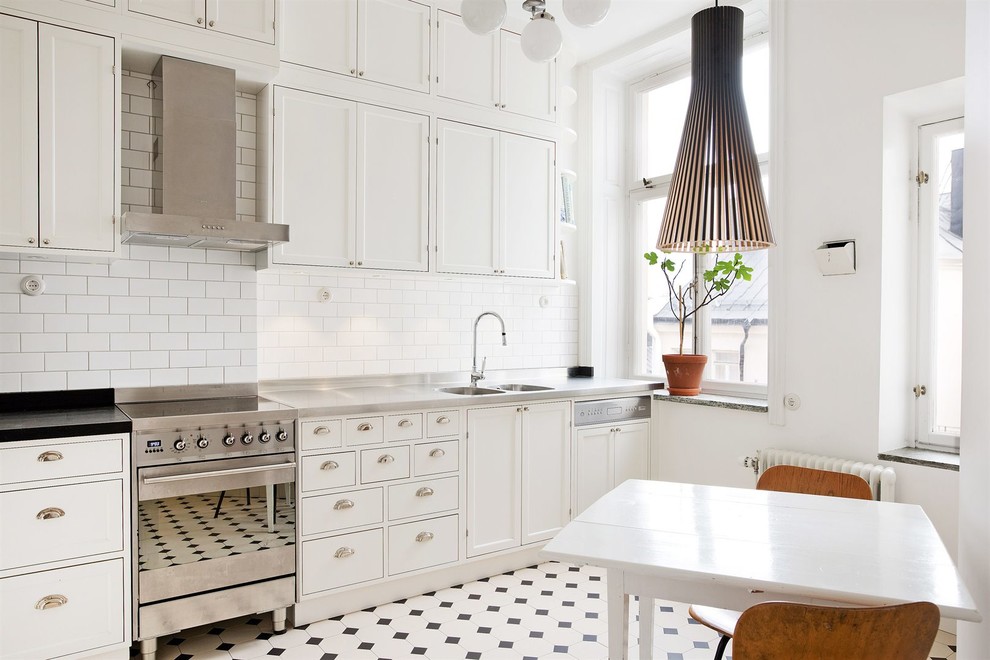Design ideas for a mid-sized scandinavian single-wall eat-in kitchen in Stockholm with a double-bowl sink, white cabinets, stainless steel benchtops, white splashback, subway tile splashback, stainless steel appliances, no island and shaker cabinets.
