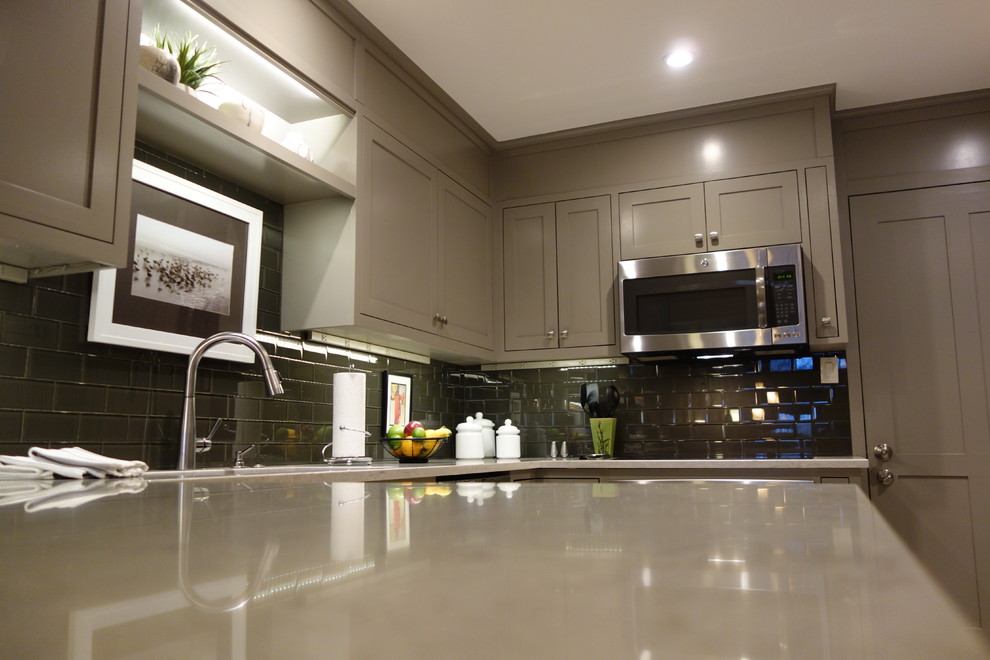 Example of a small transitional u-shaped ceramic tile enclosed kitchen design with an undermount sink, shaker cabinets, gray cabinets, quartz countertops, gray backsplash, glass tile backsplash, stainless steel appliances and a peninsula