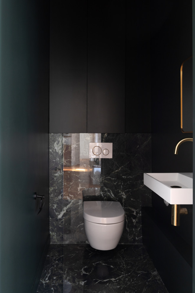 Inspiration for a mid-sized transitional powder room in Other with a wall-mount toilet, green tile, marble, green walls, marble floors, a wall-mount sink, solid surface benchtops and green floor.