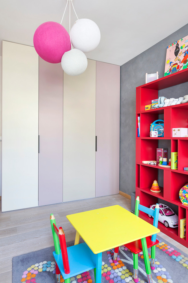 This is an example of a mid-sized contemporary kids' playroom for girls and kids 4-10 years old in Paris with grey walls and light hardwood floors.