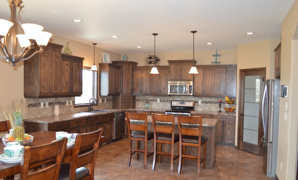 Inspiration for a mid-sized rustic l-shaped laminate floor and beige floor eat-in kitchen remodel with a drop-in sink, recessed-panel cabinets, dark wood cabinets, granite countertops, beige backsplash, stainless steel appliances, an island and ceramic backsplash
