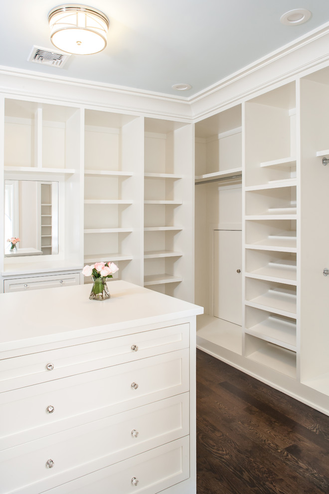 This is an example of a large transitional women's walk-in wardrobe in New York with recessed-panel cabinets, white cabinets and dark hardwood floors.