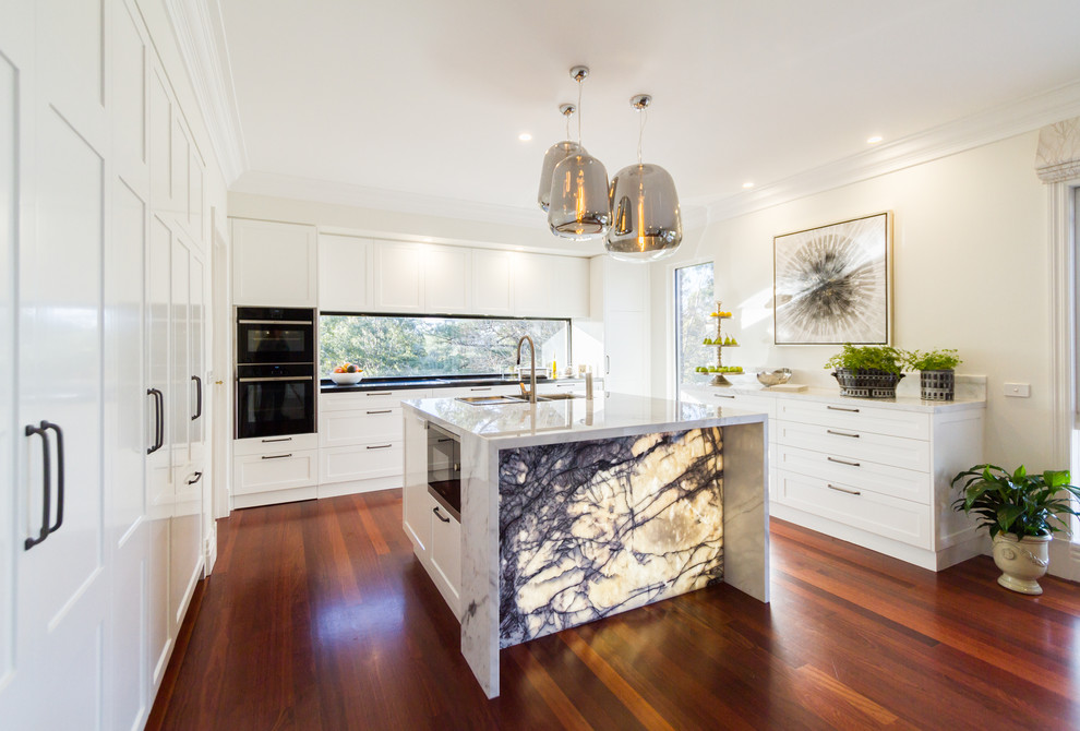 Inspiration for a large contemporary u-shaped eat-in kitchen in Melbourne with an undermount sink, white cabinets, marble benchtops, window splashback, dark hardwood floors, with island, brown floor, white benchtop, recessed-panel cabinets and stainless steel appliances.