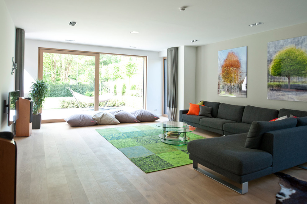 Inspiration for a contemporary formal enclosed living room in Cologne with grey walls, light hardwood floors, no fireplace, a wall-mounted tv and beige floor.