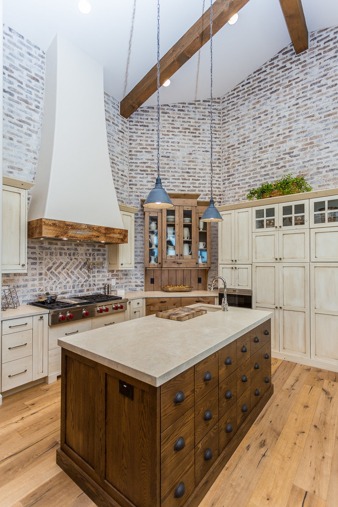 This is an example of a large country kitchen in Other with an undermount sink, shaker cabinets, beige cabinets, marble benchtops, brick splashback, stainless steel appliances, medium hardwood floors, with island and beige benchtop.