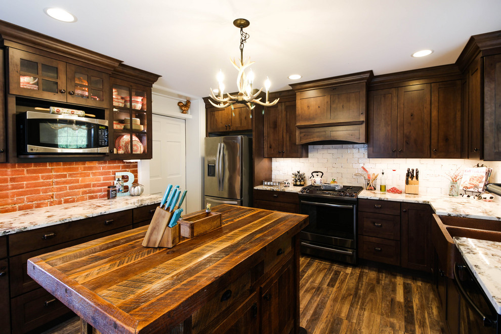 Enclosed kitchen - mid-sized rustic l-shaped vinyl floor and brown floor enclosed kitchen idea with a farmhouse sink, shaker cabinets, dark wood cabinets, granite countertops, white backsplash, ceramic backsplash, stainless steel appliances, an island and white countertops