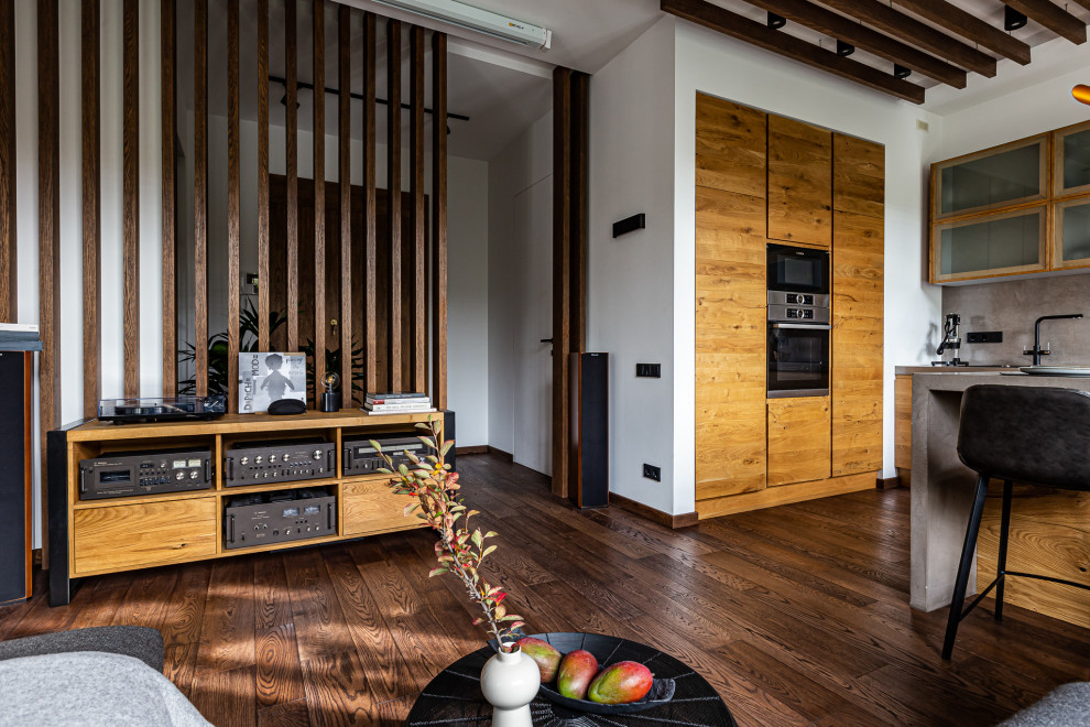 Идея дизайна: открытая, серо-белая гостиная комната среднего размера в стиле лофт с с книжными шкафами и полками, серыми стенами, полом из винила, мультимедийным центром, коричневым полом и деревянным потолком