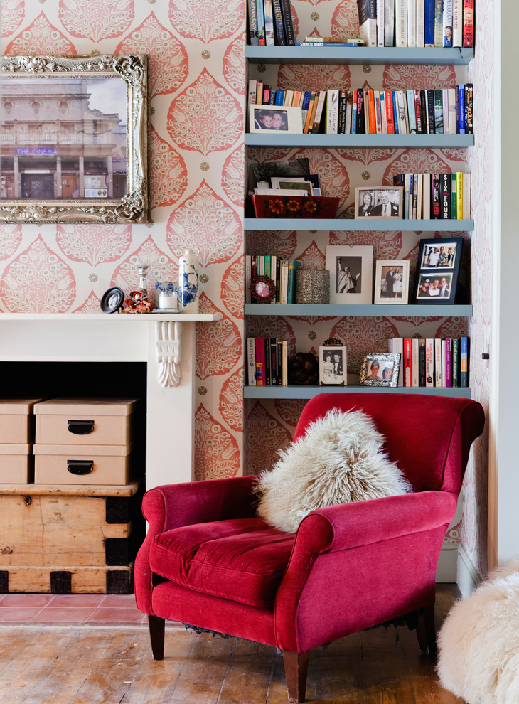 Inspiration for a small eclectic home office in London with pink walls, dark hardwood floors, a standard fireplace, a wood fireplace surround, brown floor and a library.