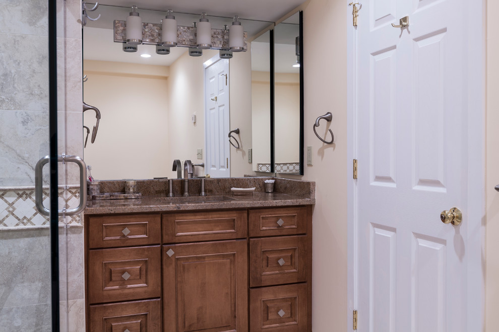 This is an example of a mid-sized traditional master bathroom in Bridgeport with an undermount sink, raised-panel cabinets, medium wood cabinets, granite benchtops, an undermount tub, a shower/bathtub combo, a two-piece toilet, beige tile, porcelain tile, beige walls and porcelain floors.