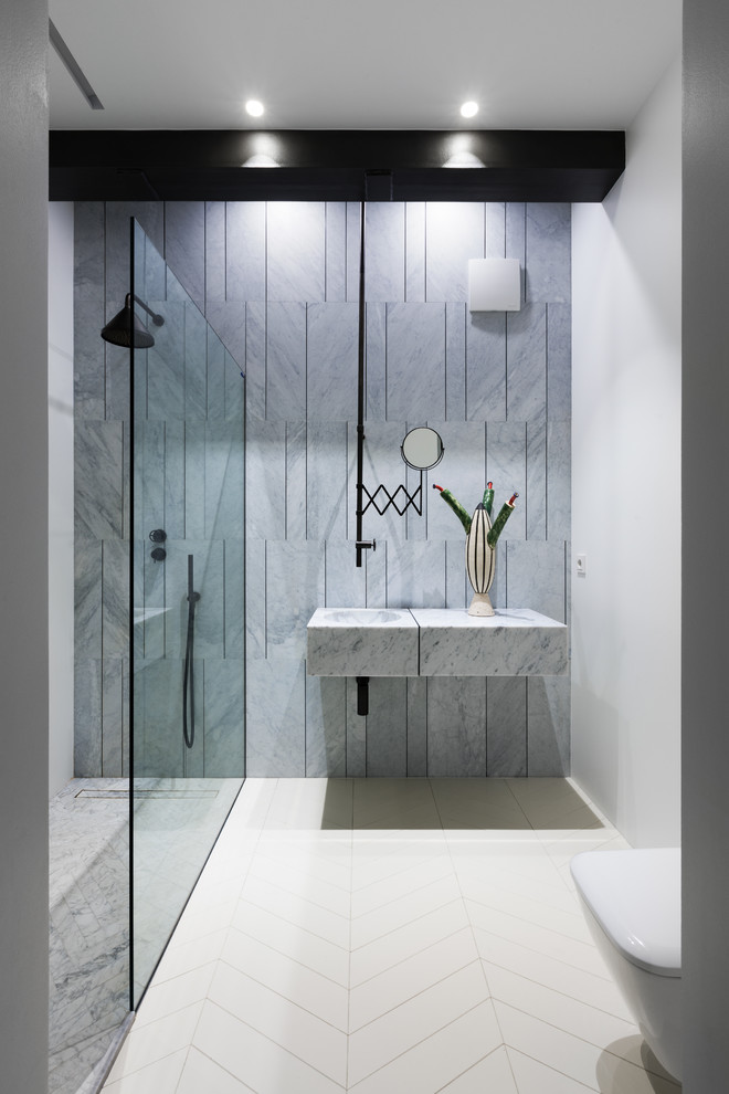 Inspiration for a mid-sized contemporary powder room in Other with glass-front cabinets, grey cabinets, a bidet, gray tile, marble, grey walls, light hardwood floors, an undermount sink, marble benchtops, white floor and grey benchtops.