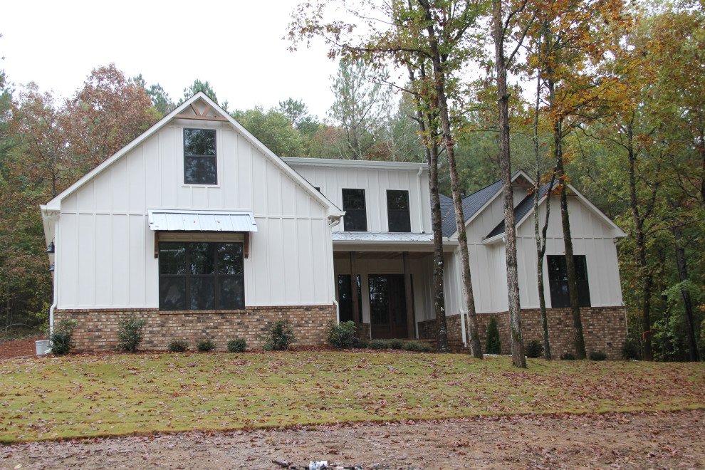 Arts and crafts one-storey white house exterior in Birmingham with concrete fiberboard siding, a shingle roof and board and batten siding.