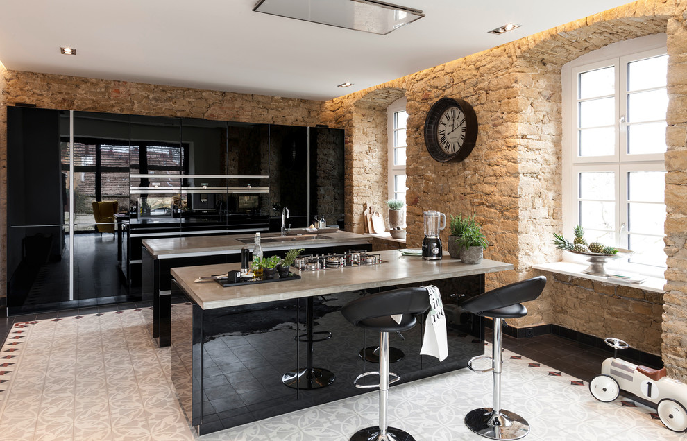 This is an example of a mid-sized contemporary single-wall open plan kitchen in Other with a drop-in sink, flat-panel cabinets, black cabinets, concrete benchtops, black appliances, multiple islands and cement tiles.