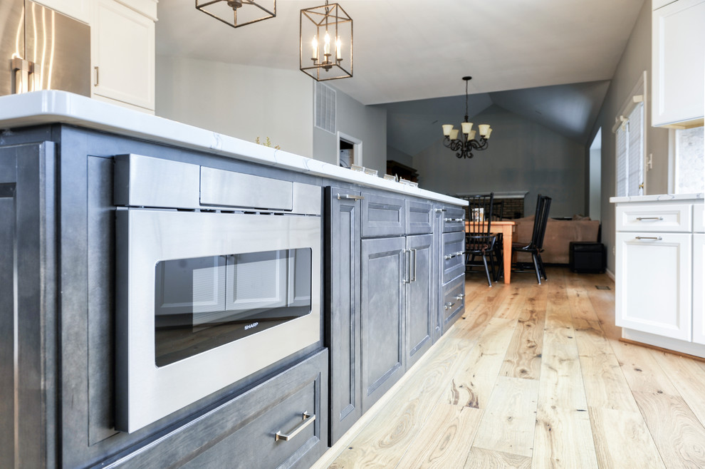 Huge transitional galley light wood floor and brown floor eat-in kitchen photo in DC Metro with an undermount sink, beaded inset cabinets, white cabinets, quartzite countertops, white backsplash, marble backsplash, stainless steel appliances, an island and white countertops