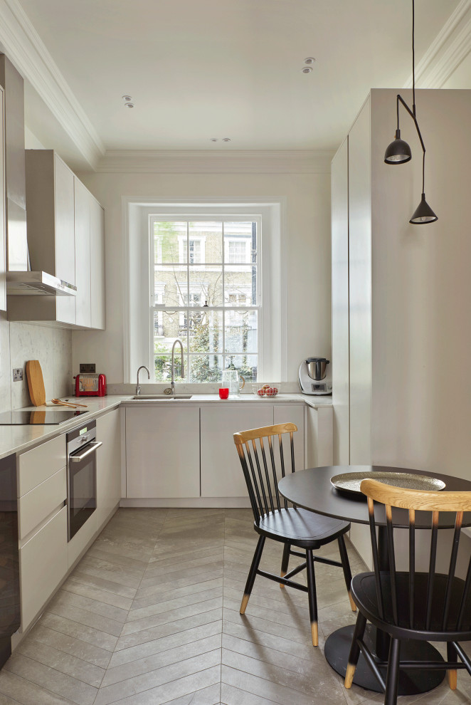 Geschlossene, Mittelgroße Moderne Küche in grau-weiß in U-Form mit integriertem Waschbecken, flächenbündigen Schrankfronten, grauen Schränken, Quarzit-Arbeitsplatte, Küchenrückwand in Grau, Kalk-Rückwand, Küchengeräten aus Edelstahl, Keramikboden, grauem Boden und grauer Arbeitsplatte in London
