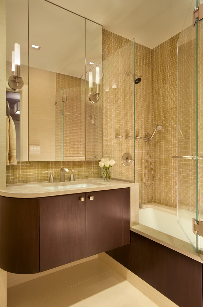 This is an example of a mid-sized contemporary master bathroom in New York with mosaic tile, flat-panel cabinets, an undermount tub, a shower/bathtub combo, beige walls, mosaic tile floors, dark wood cabinets, brown tile, an undermount sink, engineered quartz benchtops, beige floor and a hinged shower door.