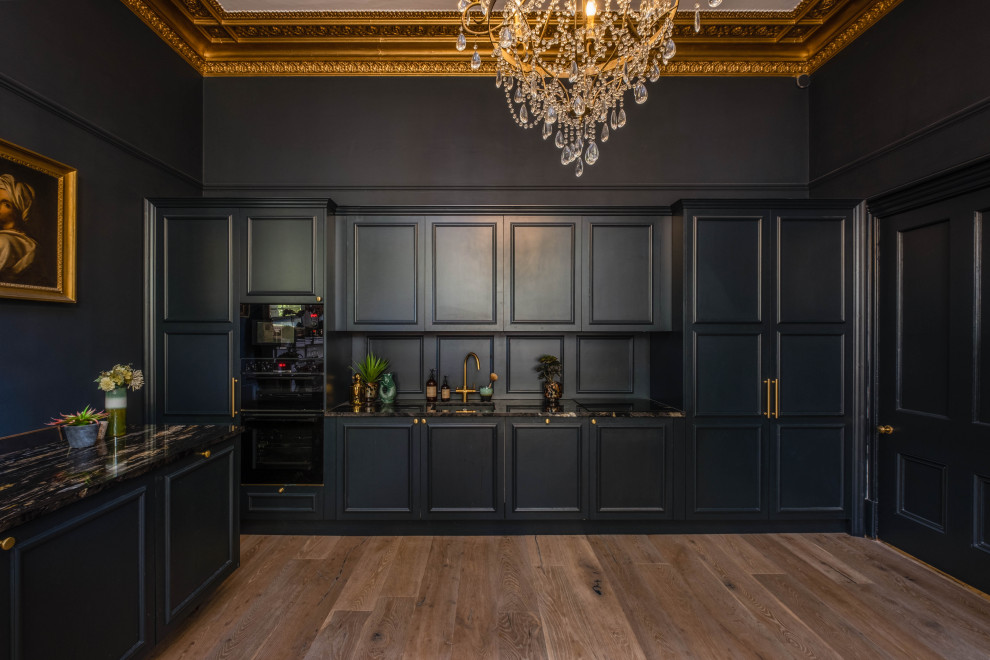Large traditional single-wall eat-in kitchen in Sussex with a drop-in sink, beaded inset cabinets, blue cabinets, granite benchtops, blue splashback, timber splashback, black appliances, light hardwood floors, with island, brown floor, black benchtop and coffered.