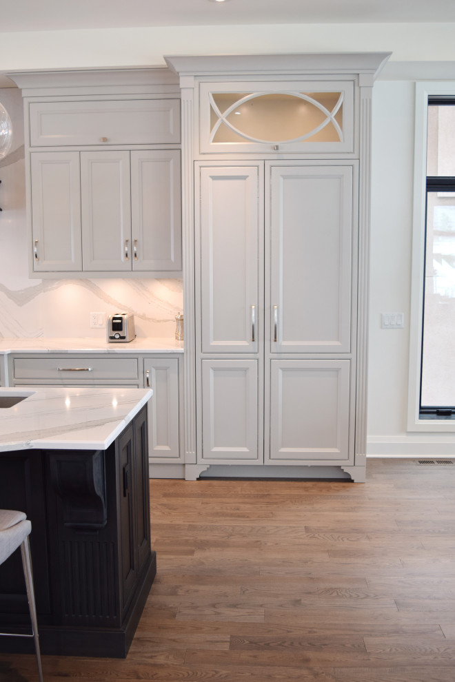 Open concept kitchen - large l-shaped medium tone wood floor and brown floor open concept kitchen idea in Ottawa with an undermount sink, recessed-panel cabinets, white cabinets, quartz countertops, white backsplash, quartz backsplash, paneled appliances, an island and white countertops