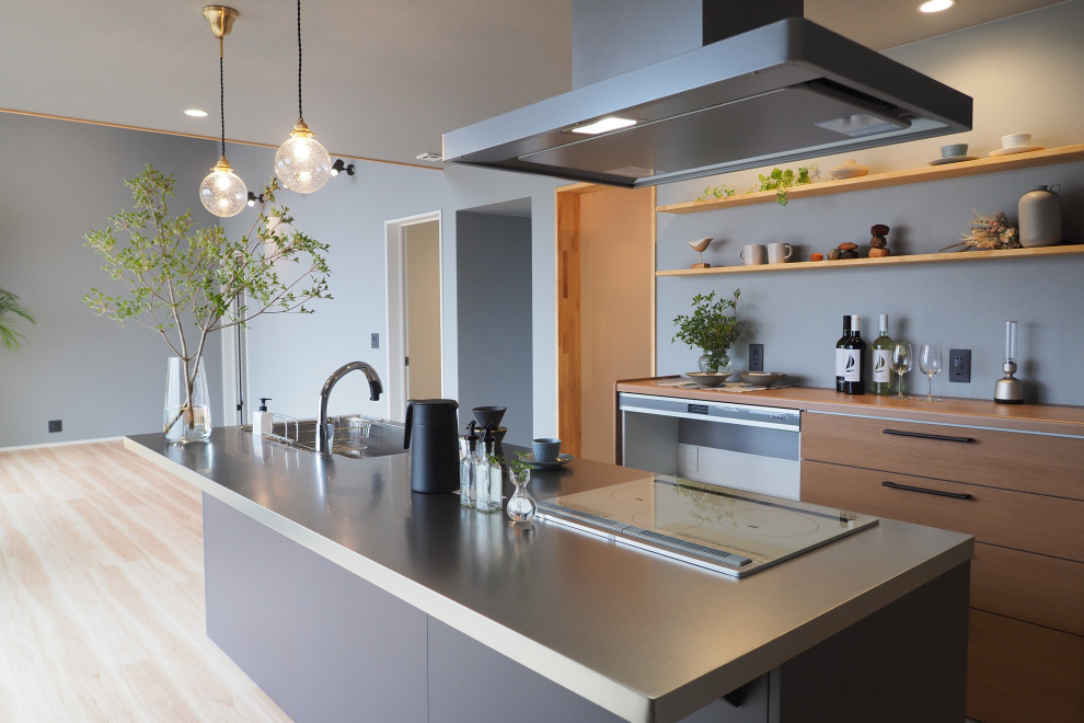 Design ideas for a modern single-wall open plan kitchen in Other with an undermount sink, flat-panel cabinets, stainless steel benchtops, vinyl floors, with island, beige floor and wallpaper.