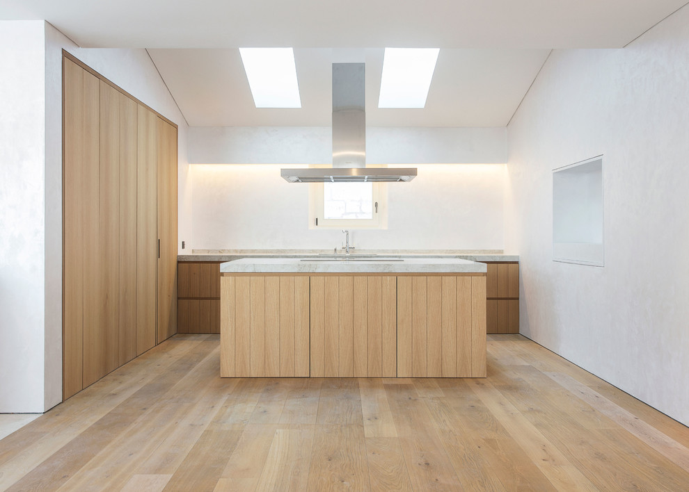 Inspiration for a large contemporary l-shaped kitchen in Palma de Mallorca with flat-panel cabinets, medium wood cabinets, limestone benchtops, panelled appliances, with island, brown floor, grey benchtop and medium hardwood floors.