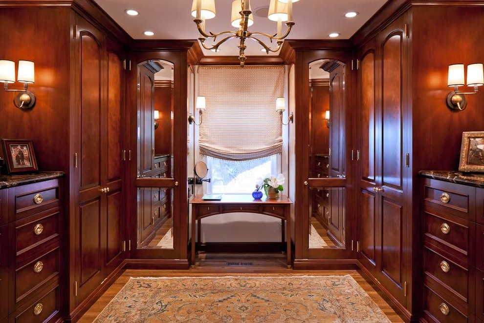 This is an example of a traditional men's dressing room in San Francisco with dark wood cabinets, raised-panel cabinets and medium hardwood floors.