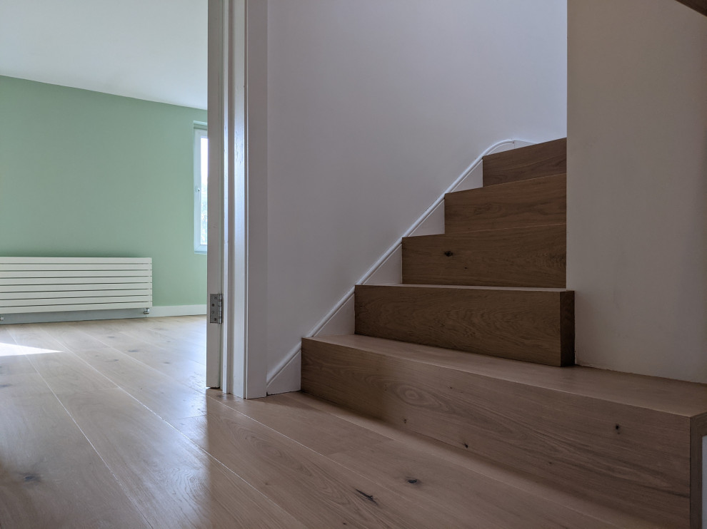 Modelo de escalera curva moderna pequeña con escalones de madera, contrahuellas de madera y barandilla de madera