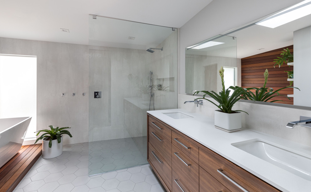 Design ideas for a midcentury master bathroom in Sacramento with flat-panel cabinets, medium wood cabinets, a freestanding tub, a curbless shower, a one-piece toilet, white tile, porcelain tile, grey walls, ceramic floors, a drop-in sink, engineered quartz benchtops, grey floor, an open shower, white benchtops, a niche, a double vanity and a freestanding vanity.