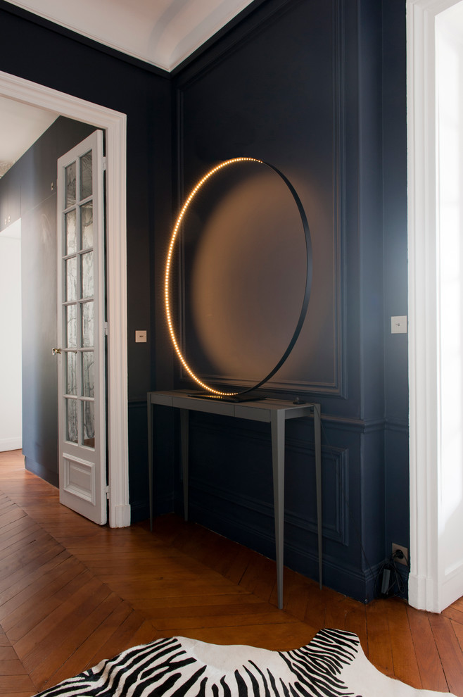 Photo of a mid-sized contemporary hallway in Paris with blue walls and medium hardwood floors.