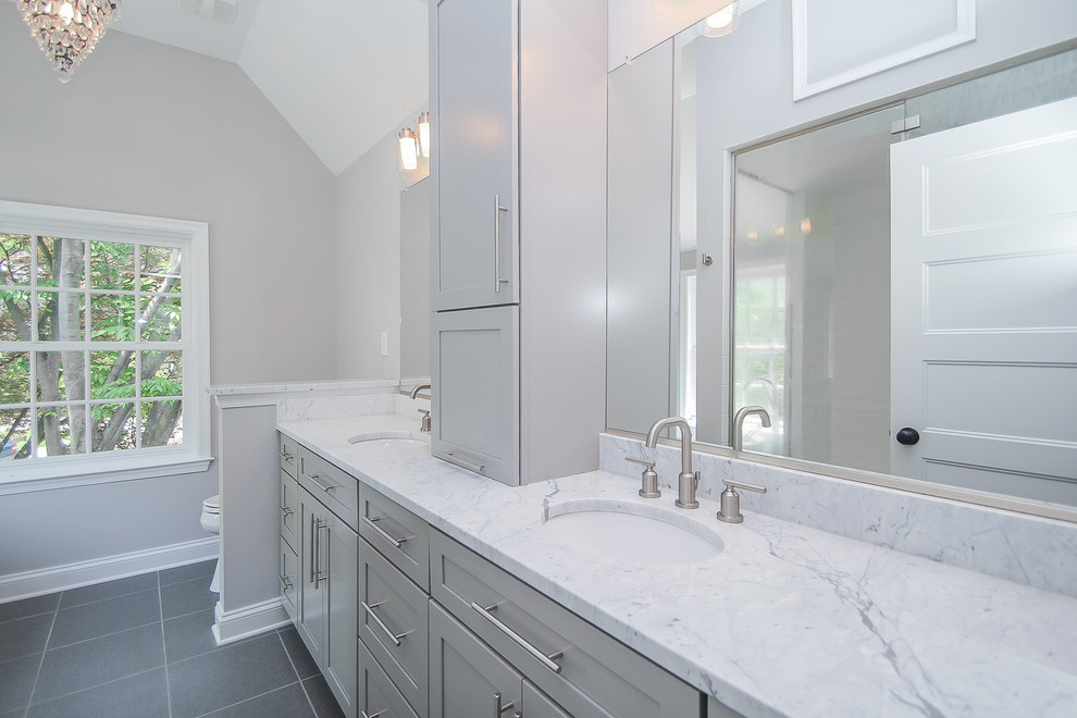 Mid-sized contemporary master bathroom in Baltimore with shaker cabinets, grey cabinets, a freestanding tub, a one-piece toilet, white tile, ceramic tile, grey walls, an undermount sink, marble benchtops and ceramic floors.