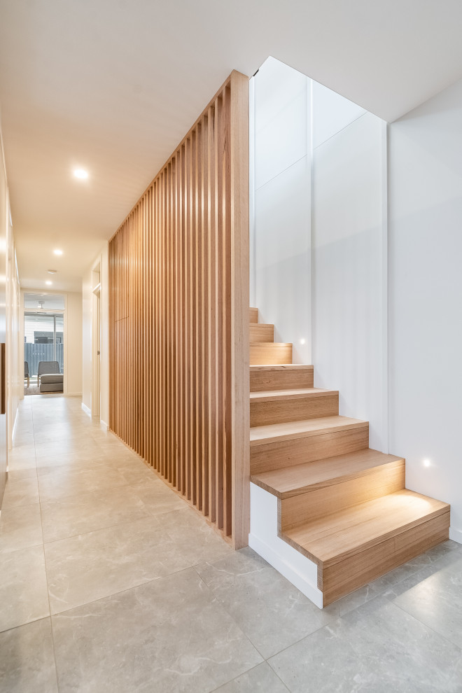 This is an example of a mid-sized beach style wood straight staircase in Sydney with wood risers, wood railing and wood walls.