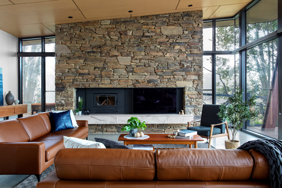 Photo of a large contemporary open concept living room in Melbourne with white walls, concrete floors, a standard fireplace, a stone fireplace surround, a concealed tv and grey floor.