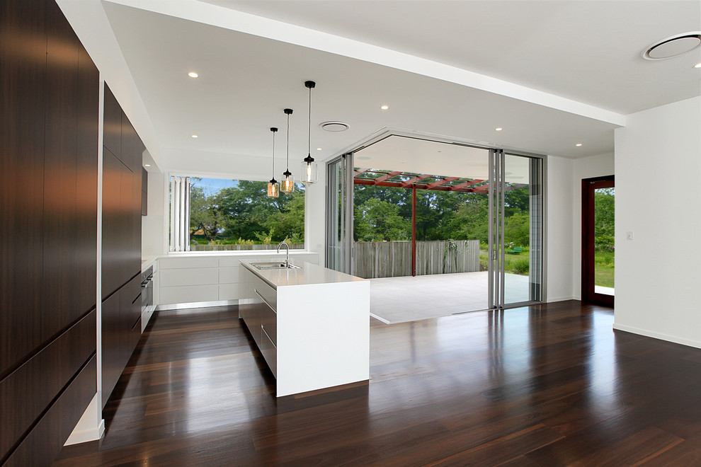 Inspiration for a mid-sized modern l-shaped open plan kitchen in Brisbane with an undermount sink, flat-panel cabinets, dark wood cabinets, granite benchtops, white splashback, stainless steel appliances, dark hardwood floors and with island.
