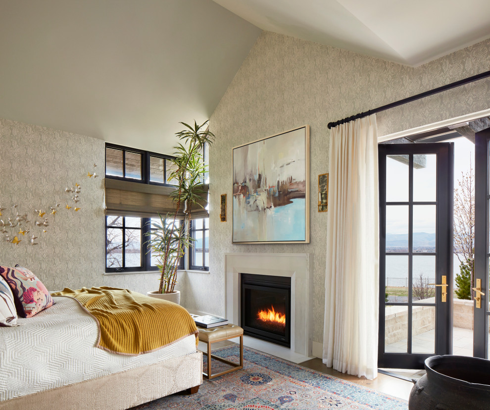 Klassisches Hauptschlafzimmer mit grauer Wandfarbe, braunem Holzboden, Kamin, Kaminumrandung aus Stein, gewölbter Decke, Tapetenwänden und braunem Boden in Denver