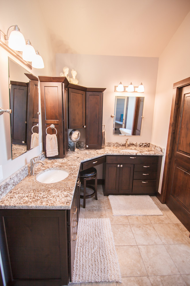 Photo of a mid-sized traditional master bathroom in Other with flat-panel cabinets, dark wood cabinets, a corner shower, a one-piece toilet, beige tile, beige walls, an undermount sink, granite benchtops, beige floor, a hinged shower door, brown benchtops and ceramic floors.