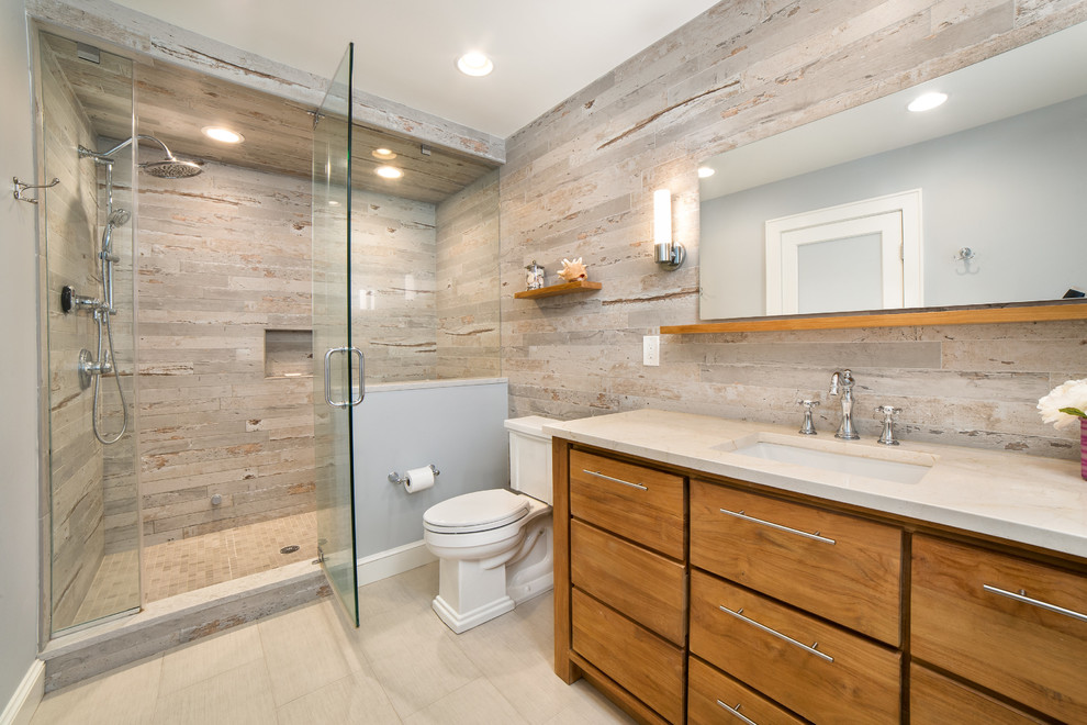 Design ideas for a mid-sized beach style bathroom in New York with flat-panel cabinets, medium wood cabinets, an open shower, a two-piece toilet, blue tile, porcelain tile, blue walls, porcelain floors, an undermount sink, quartzite benchtops, beige floor, a hinged shower door and beige benchtops.