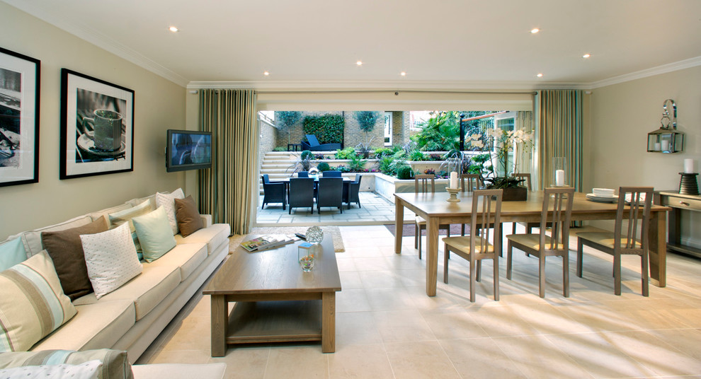 Traditional open concept living room in London with beige walls, a wall-mounted tv and beige floor.