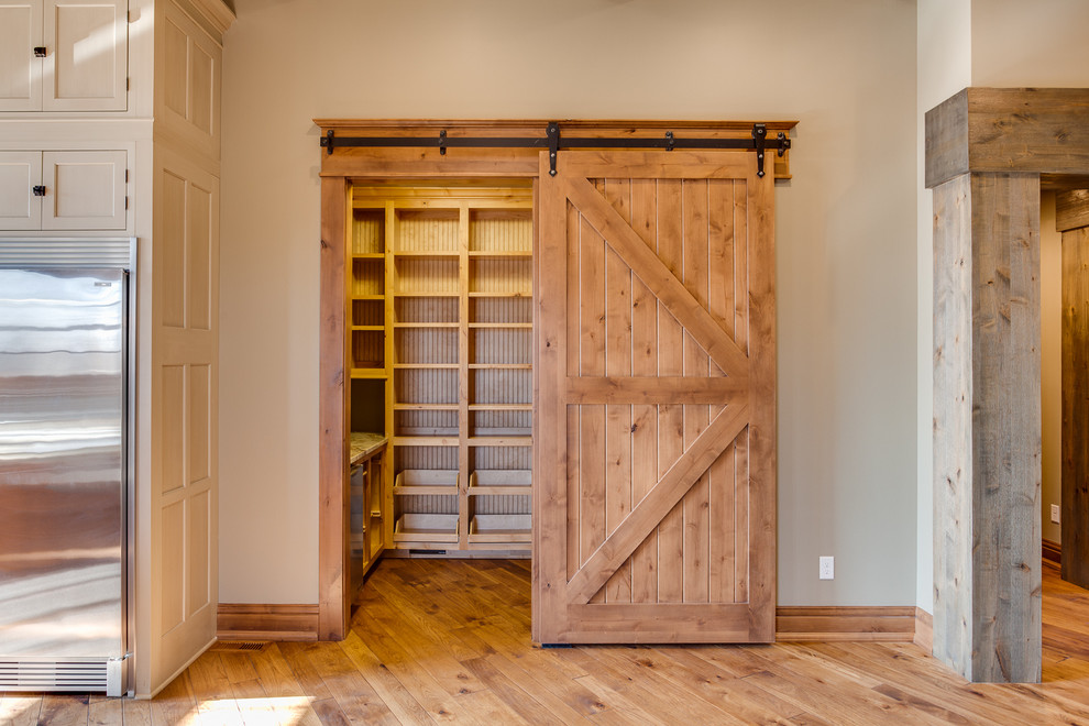 Example of a huge mountain style u-shaped medium tone wood floor kitchen pantry design with a farmhouse sink, beaded inset cabinets, beige cabinets, granite countertops, stainless steel appliances and an island